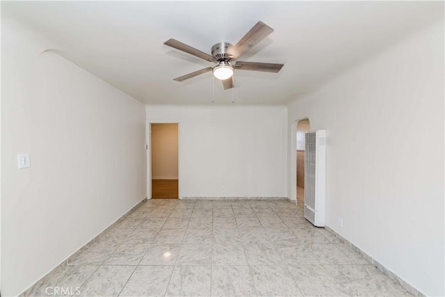 spare room featuring arched walkways and a ceiling fan