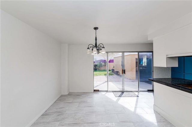 unfurnished dining area with a chandelier and baseboards