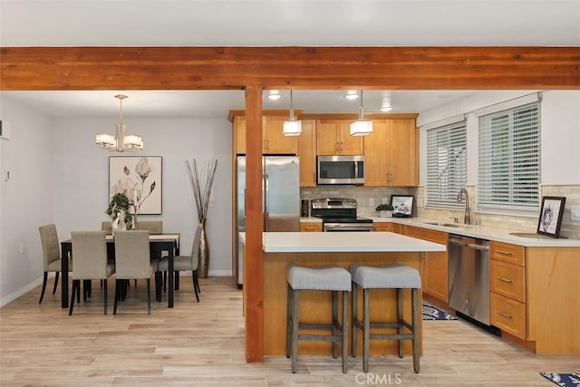 kitchen with appliances with stainless steel finishes, a breakfast bar area, a sink, and tasteful backsplash