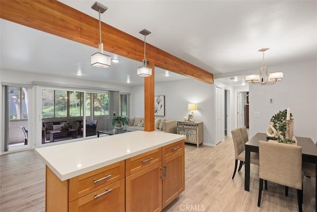 kitchen with open floor plan, decorative light fixtures, light countertops, light wood-type flooring, and beam ceiling