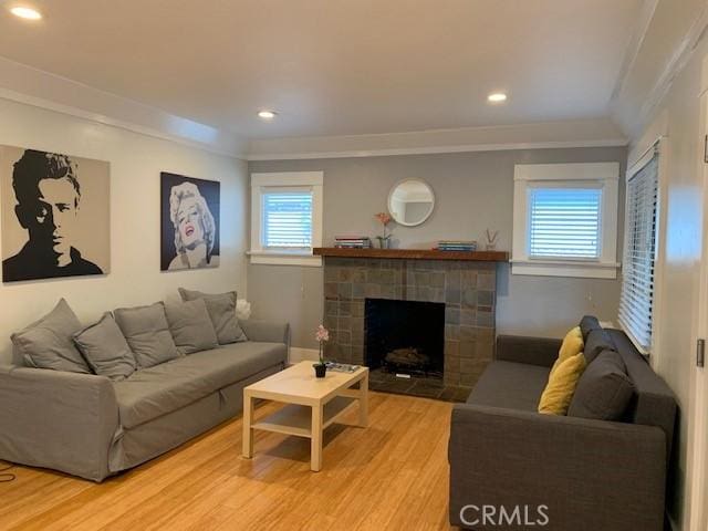 living room with a fireplace with flush hearth, ornamental molding, wood finished floors, and recessed lighting