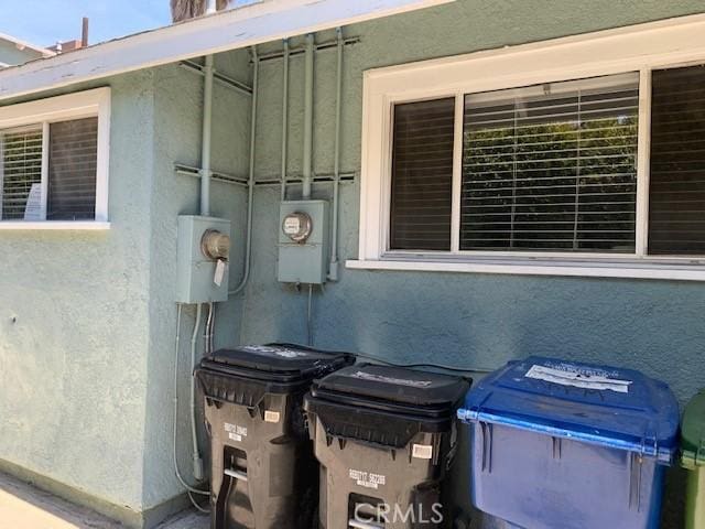 details featuring electric meter and stucco siding