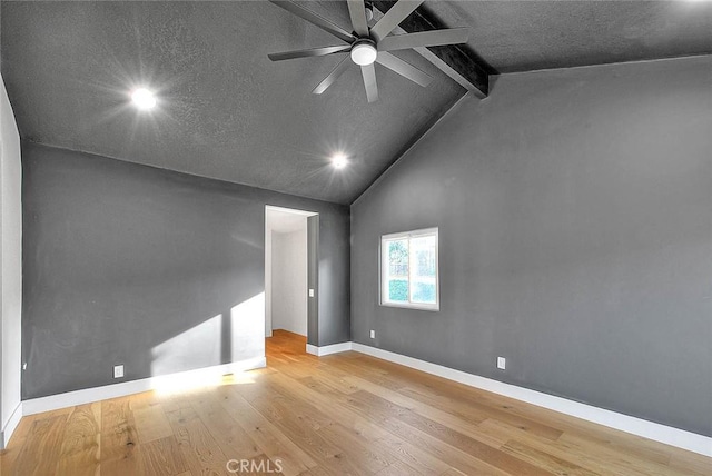 empty room featuring a ceiling fan, wood finished floors, high vaulted ceiling, beamed ceiling, and baseboards