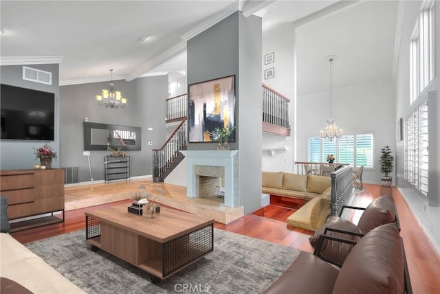 living room with ornamental molding, wood finished floors, visible vents, and a notable chandelier