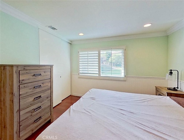 bedroom with a wainscoted wall, dark wood finished floors, recessed lighting, visible vents, and ornamental molding