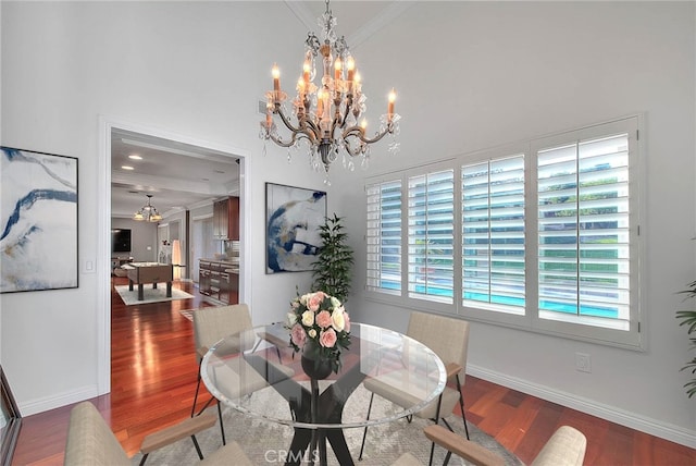 dining space with baseboards, crown molding, a chandelier, and wood finished floors