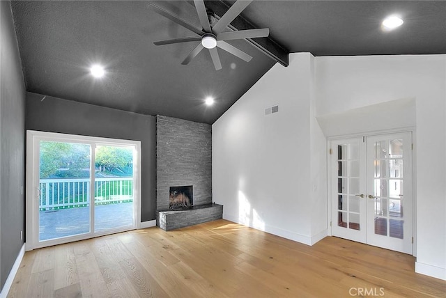 unfurnished living room with visible vents, beamed ceiling, wood finished floors, a stone fireplace, and high vaulted ceiling