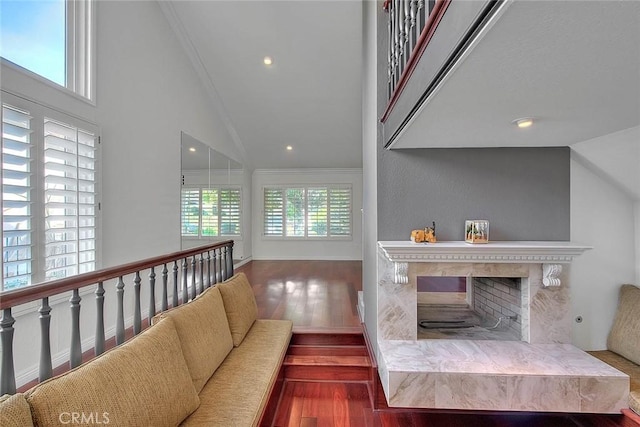 living area featuring high vaulted ceiling, a fireplace with raised hearth, wood finished floors, and recessed lighting