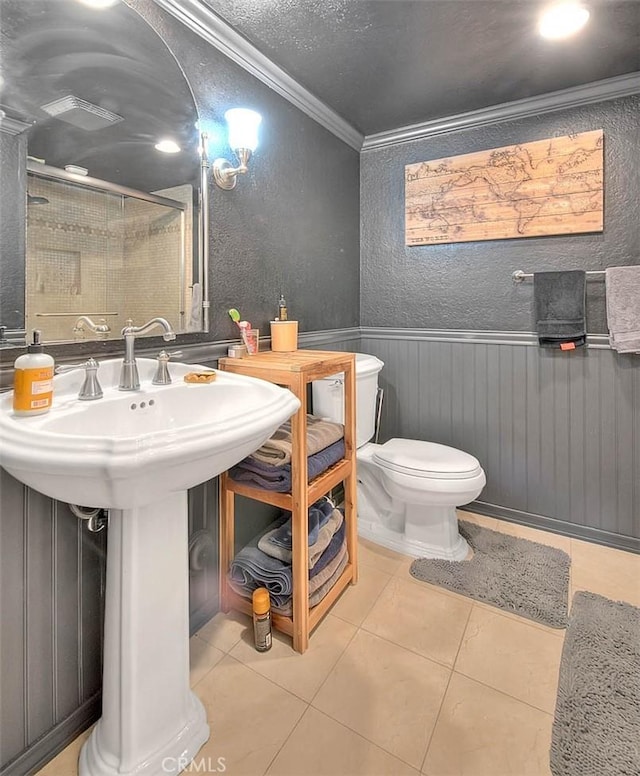 bathroom featuring crown molding, a textured wall, a stall shower, wainscoting, and tile patterned flooring