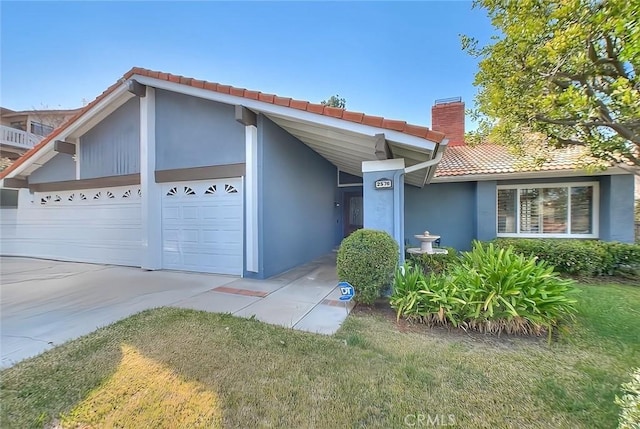 view of front of house featuring a garage, a chimney, a tile roof, and stucco siding