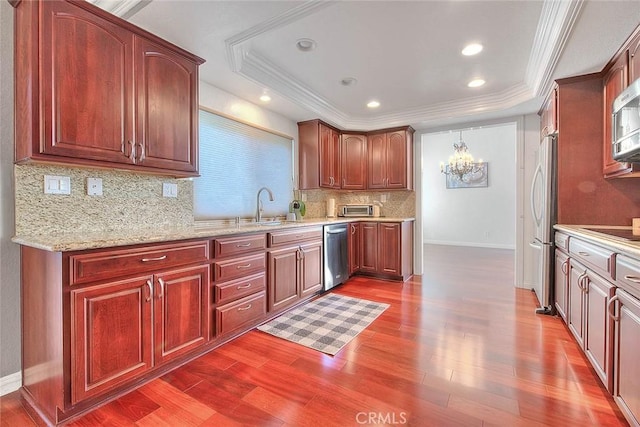 kitchen featuring stainless steel appliances, a raised ceiling, dark wood-type flooring, and a sink