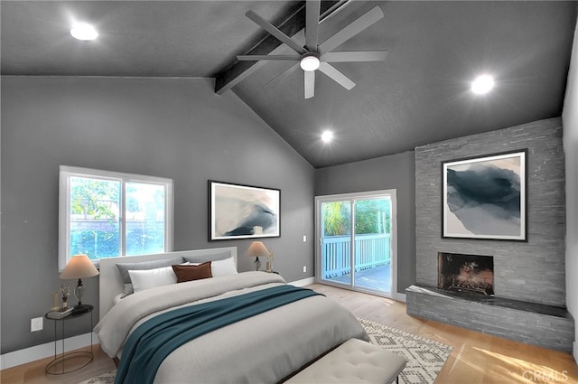 bedroom with lofted ceiling with beams, a stone fireplace, wood finished floors, baseboards, and access to outside