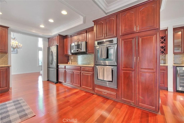 kitchen featuring light wood-style floors, a tray ceiling, stainless steel appliances, and crown molding