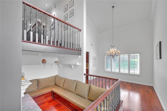 living room featuring crown molding, wood finished floors, a towering ceiling, baseboards, and an inviting chandelier