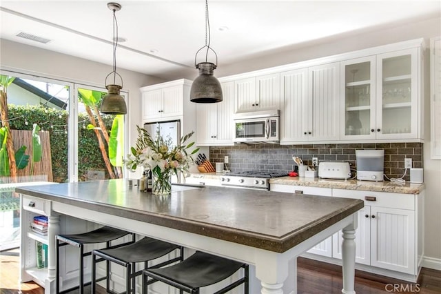 kitchen with appliances with stainless steel finishes, white cabinets, visible vents, and tasteful backsplash