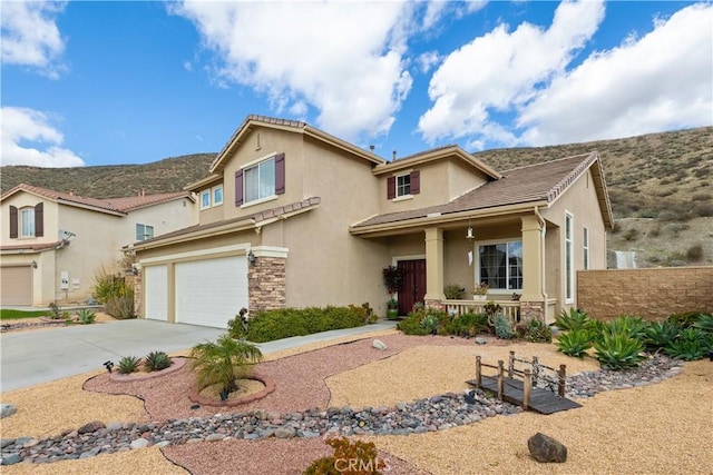 view of front facade featuring driveway, a garage, stone siding, fence, and stucco siding