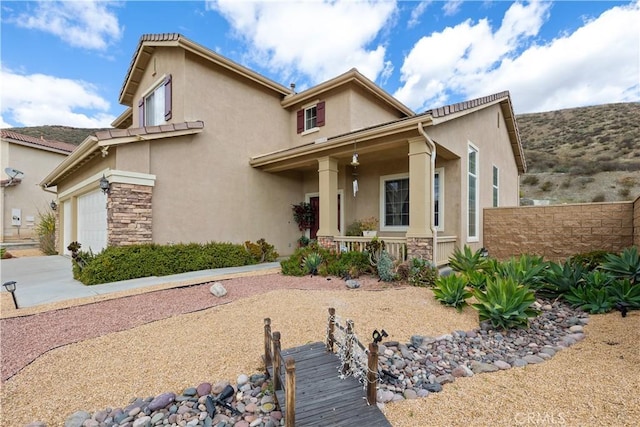 view of front of home with covered porch, stone siding, fence, and stucco siding