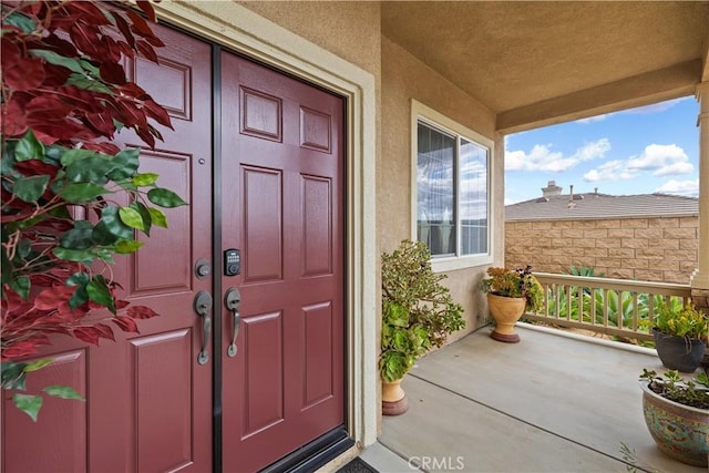 property entrance featuring covered porch and stucco siding