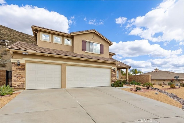 traditional-style home with stucco siding, concrete driveway, an attached garage, stone siding, and a tiled roof