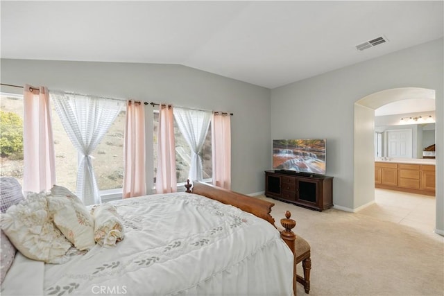 bedroom featuring light carpet, visible vents, arched walkways, connected bathroom, and lofted ceiling