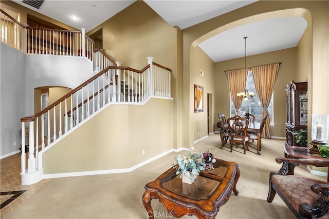 living room featuring visible vents, a towering ceiling, baseboards, stairway, and carpet