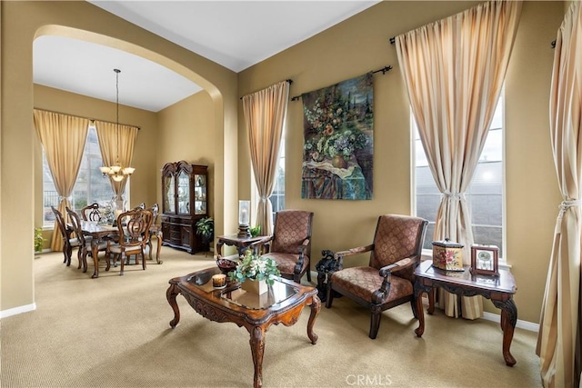 living area with carpet floors, baseboards, arched walkways, and a notable chandelier