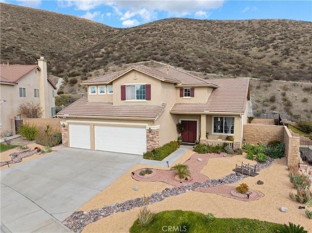 traditional home with an attached garage, fence, a tiled roof, stone siding, and driveway