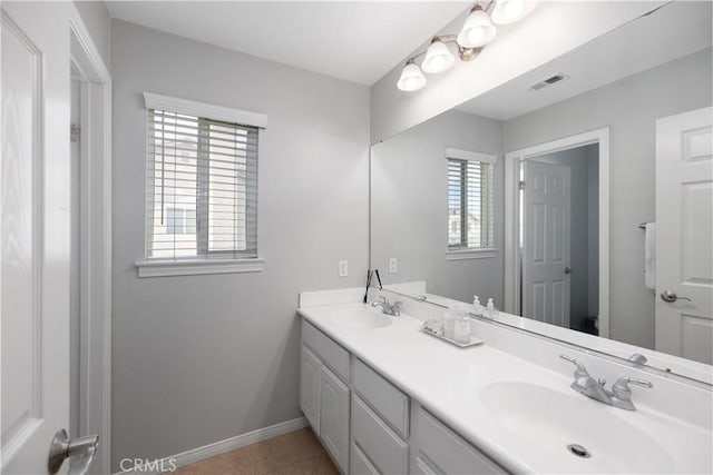 bathroom with double vanity, a sink, visible vents, and baseboards