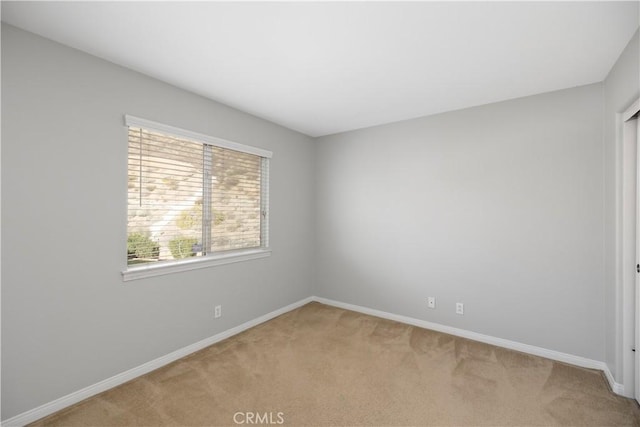 spare room featuring baseboards and light colored carpet