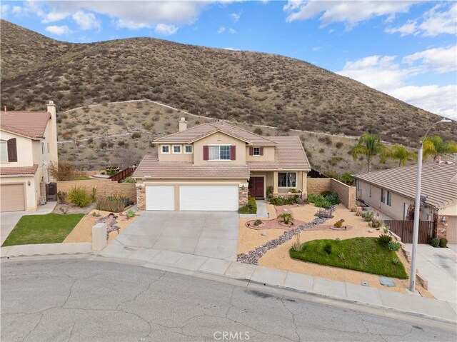 view of front facade with a tile roof, stucco siding, a mountain view, fence, and a garage