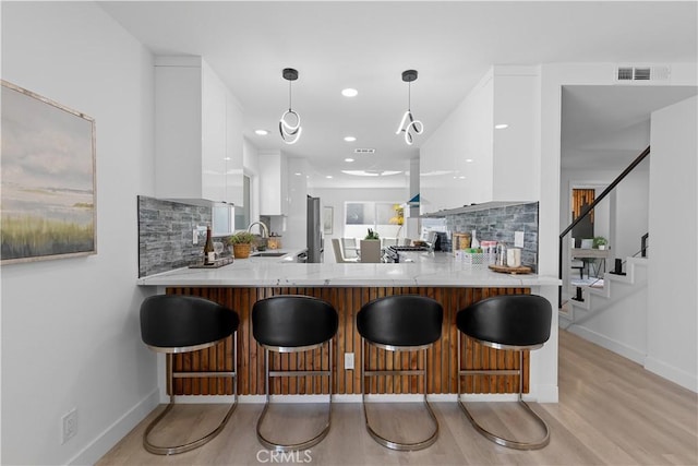 kitchen featuring white cabinets, a sink, a peninsula, and modern cabinets