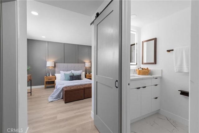 bedroom with marble finish floor, a barn door, baseboards, and recessed lighting