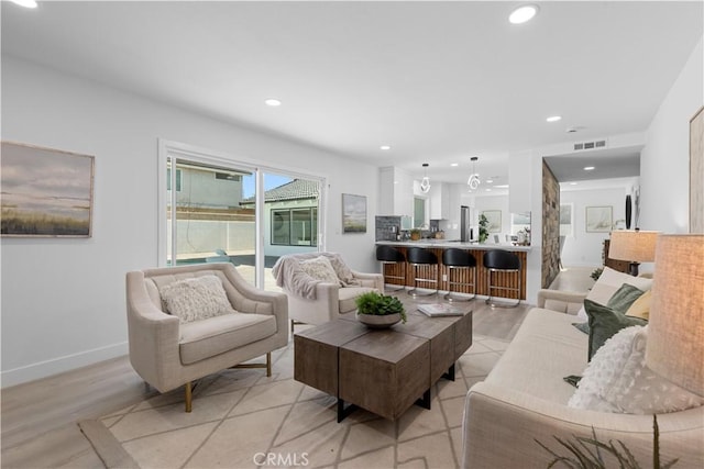 living area with baseboards, visible vents, and recessed lighting