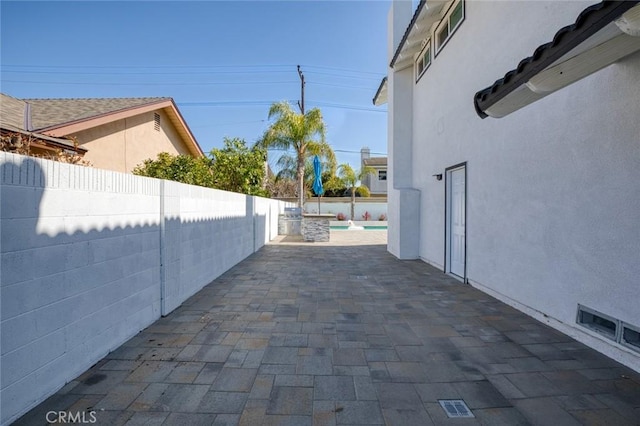 view of side of home featuring a patio area, a fenced backyard, and stucco siding