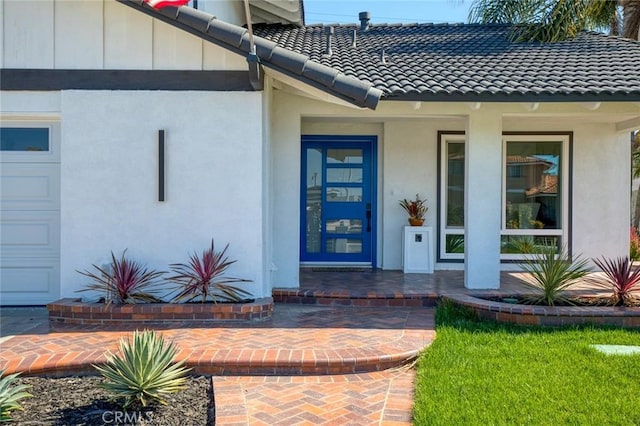 view of exterior entry featuring covered porch, a tile roof, and stucco siding