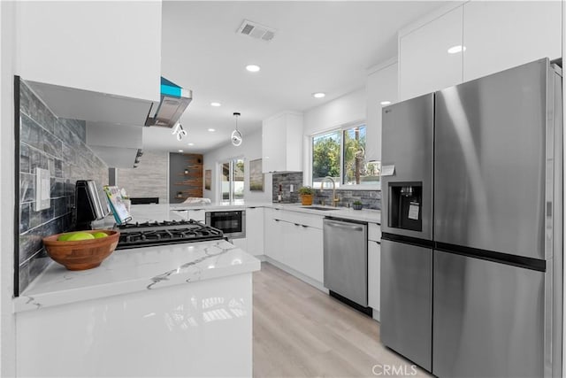 kitchen featuring stainless steel appliances, white cabinets, visible vents, and a sink