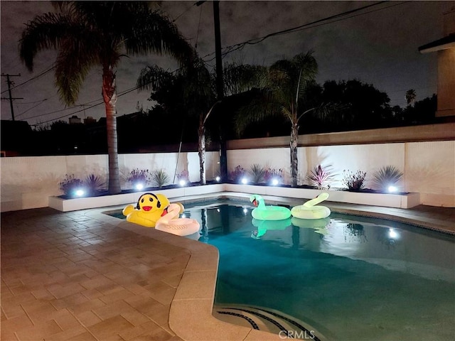 pool at night with a fenced in pool