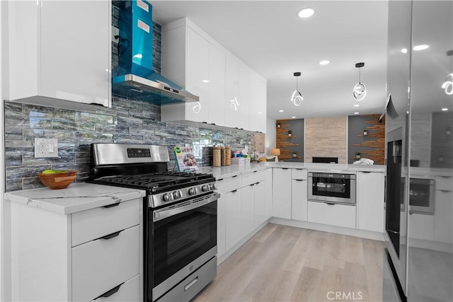 kitchen with light stone counters, stainless steel appliances, white cabinets, modern cabinets, and wall chimney exhaust hood