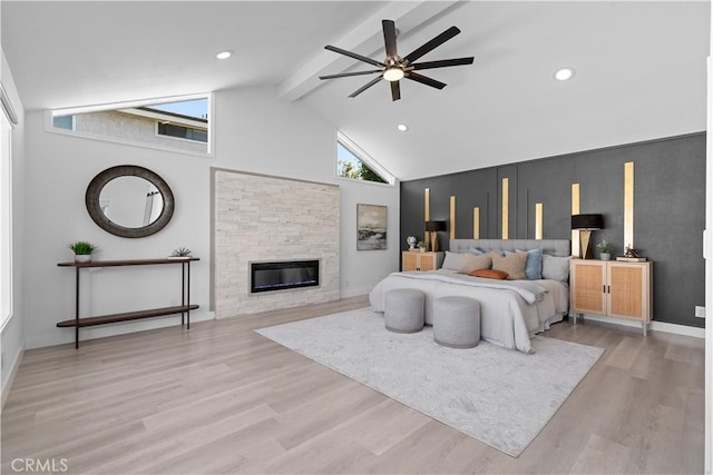 bedroom with high vaulted ceiling, recessed lighting, light wood-style floors, beam ceiling, and a glass covered fireplace