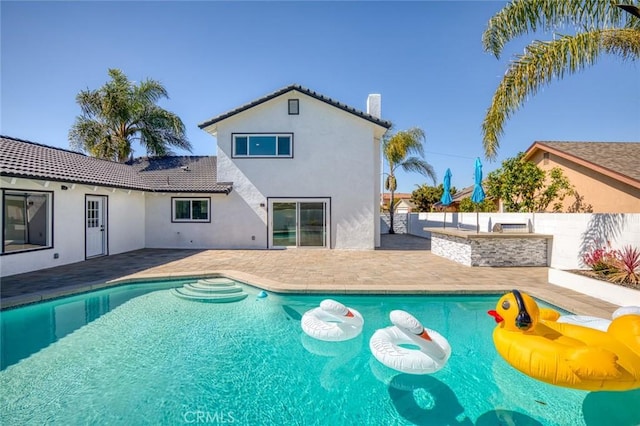 view of swimming pool featuring a patio area, fence, an outdoor kitchen, and outdoor wet bar