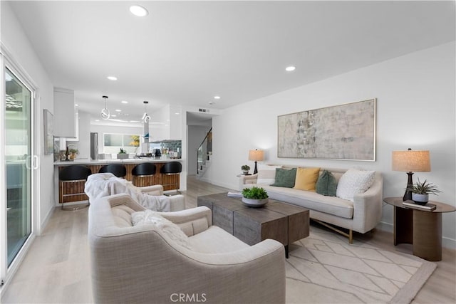 living area with light wood finished floors, stairs, and recessed lighting