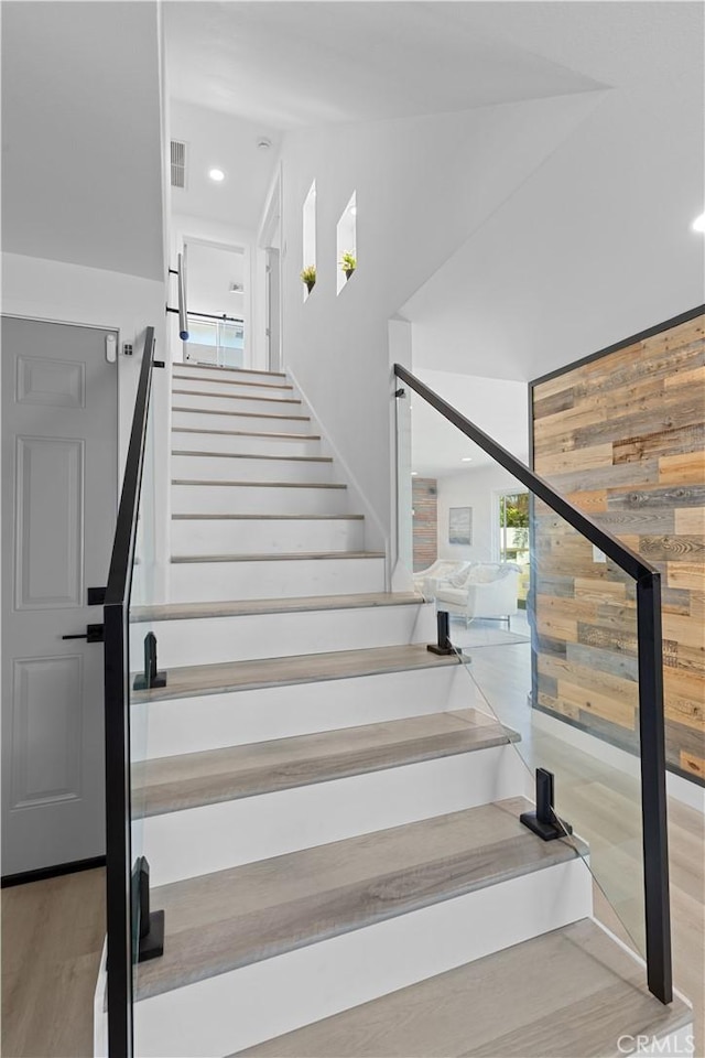 staircase with wood walls, visible vents, and recessed lighting