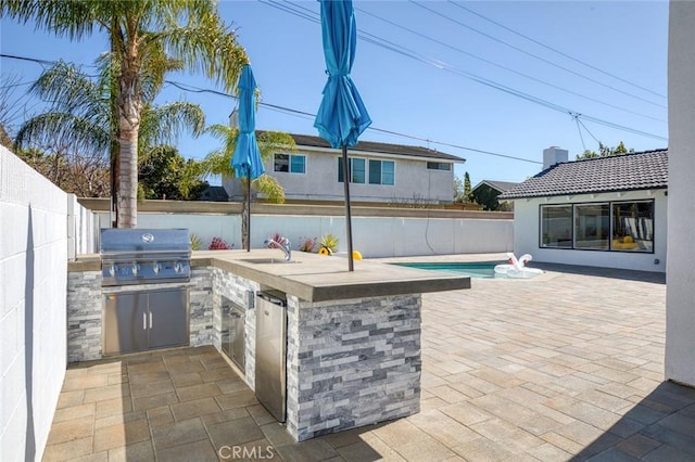 view of patio / terrace featuring exterior kitchen, a fenced backyard, a sink, and area for grilling