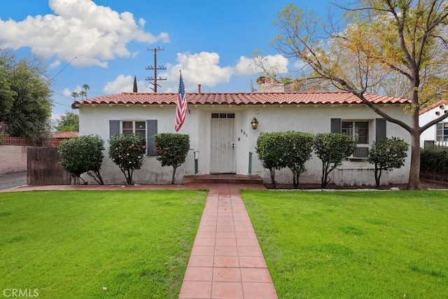 mediterranean / spanish house featuring a tile roof, a front lawn, and stucco siding