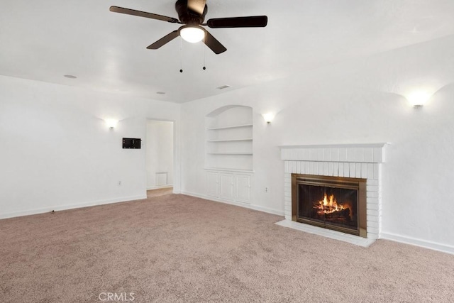 unfurnished living room featuring built in features, a fireplace, a ceiling fan, and carpet