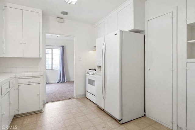 kitchen featuring tile countertops, light floors, light carpet, white appliances, and white cabinetry