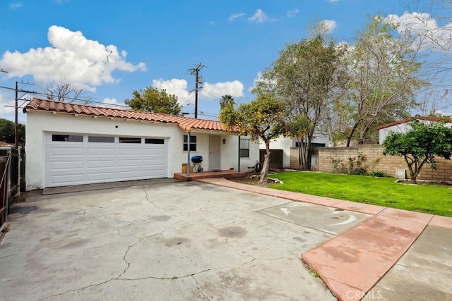 mediterranean / spanish house with fence, an attached garage, stucco siding, concrete driveway, and a tiled roof