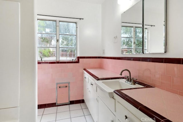 kitchen with light tile patterned floors, a wainscoted wall, tile counters, white cabinetry, and tile walls