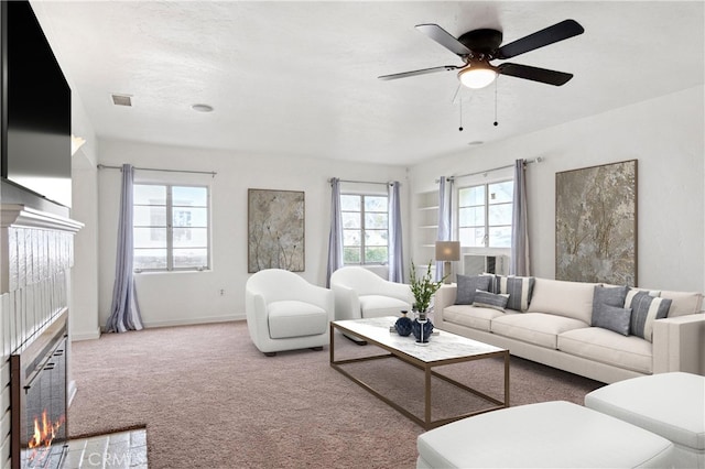 living room with baseboards, visible vents, carpet floors, a warm lit fireplace, and ceiling fan