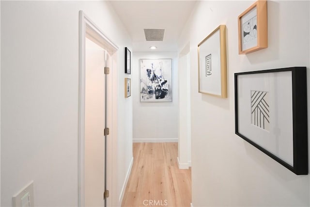 hallway with light wood finished floors, recessed lighting, visible vents, and baseboards